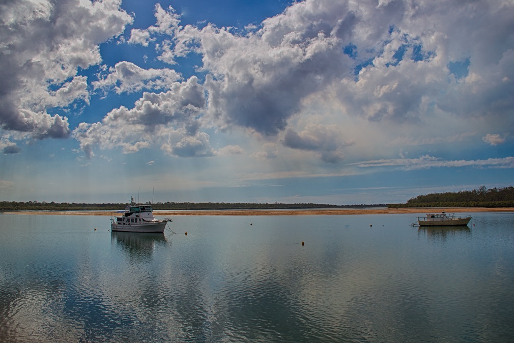 Clouds reflected in river with boats