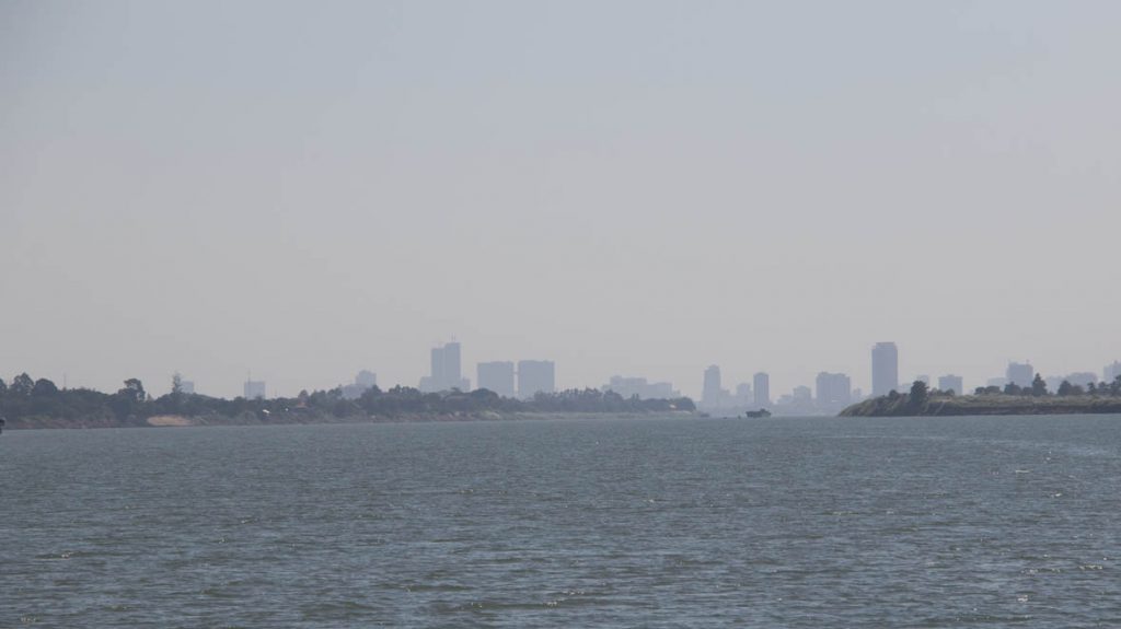 Phnom Phenh's high rises are visible through the haze upriver