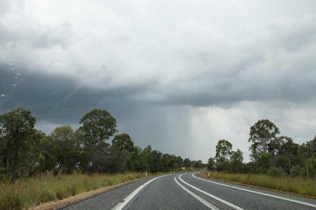 A storm cloud is in view at the end of a stretch of highway