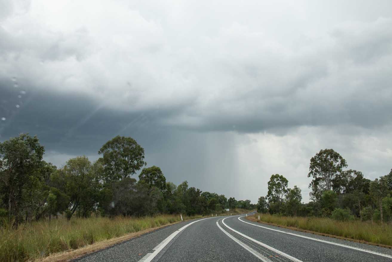 A storm cloud is in view at the end of a stretch of highway