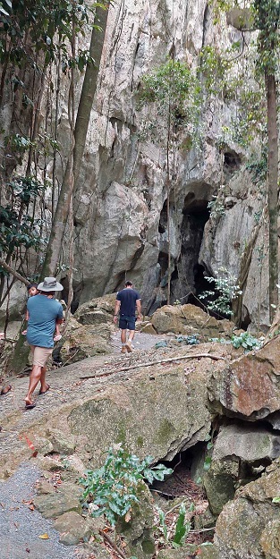 Two people walk along the limestone track leading to the entrance to the Capricorn Caves
