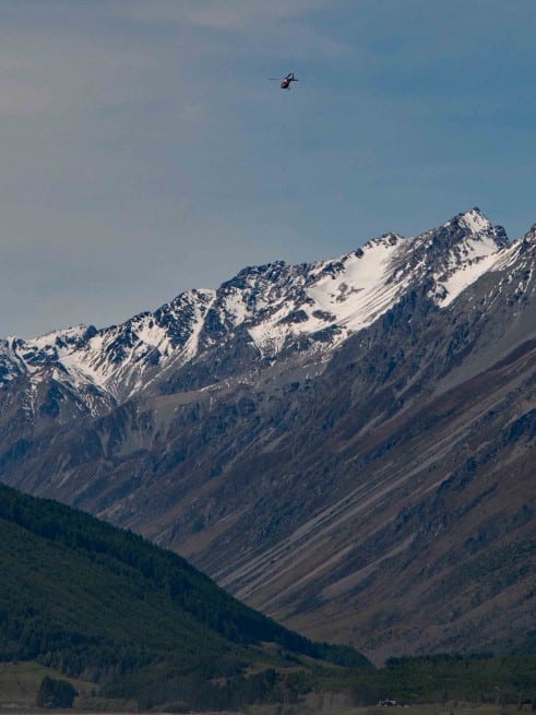 A helicopter flies high above the Southern Alps