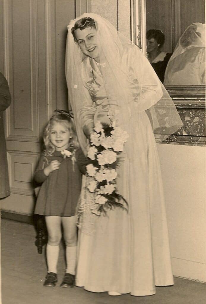 A child stands next to  a woman in a wedding gown