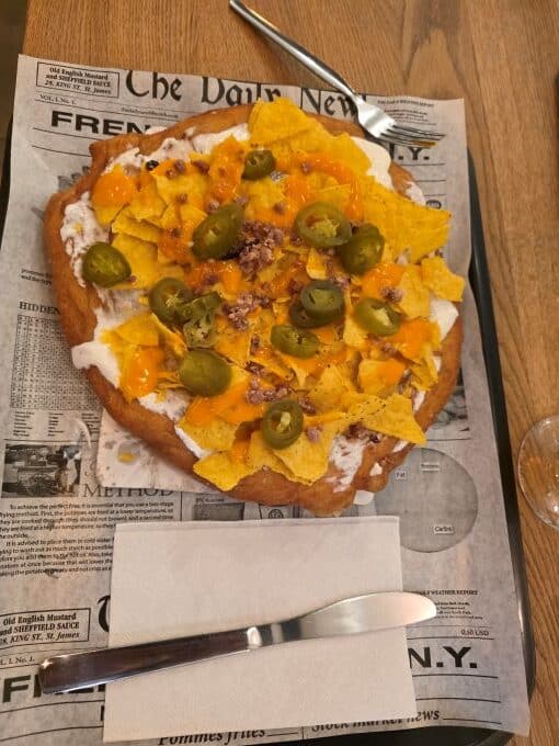 Langos - a circle of fried pastry covered in sour cream, crumbled corn chips and slices of jalapeno peppers