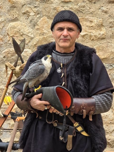 A man in traditional costume holds a peregrine falcon at Golubac fort
