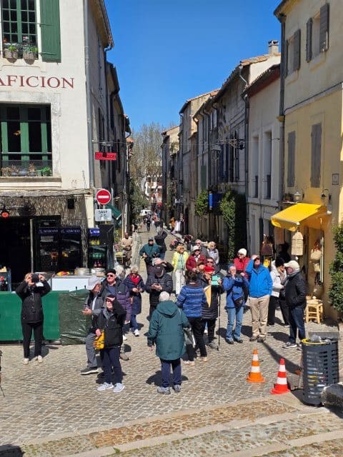 Arles street showing a tour group gazing up at the amphitheatre