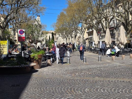 Avignon town square showing lines of restaurants with umbrellas furled because of the wind
