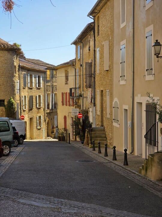 Chateau Neuf du Pape village street showing houses built of limestone with wooden shutters on the windows