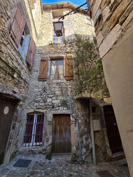 Viviers street scene with shuttered windows and raw pale brick walls
